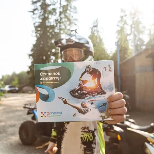 Человек держит буклет о характеристиках квадроцикла на фоне леса, готовясь к активному отдыху