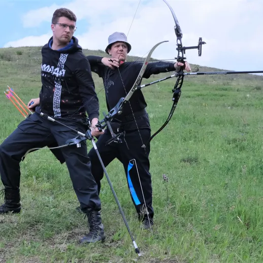 Стрельба из лука на зеленом поле с участником и тренером в солнечный день