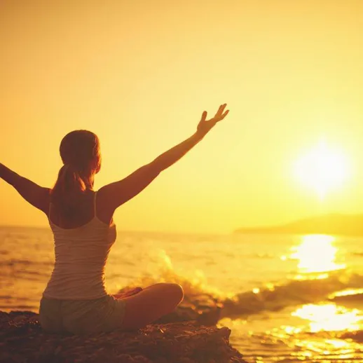 Женщина на берегу моря наслаждается закатом и ощущает гармонию с природой в теплый летний вечер