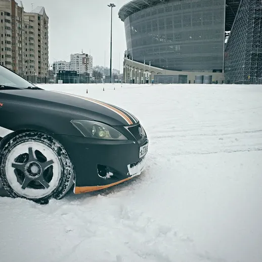 Зимний день в городе с авто на снежной парковке рядом со спортивным стадионом