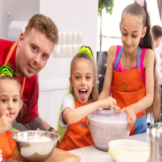 Дети учатся готовить с шеф-поваром на кулинарном мастер-классе в уютной студии