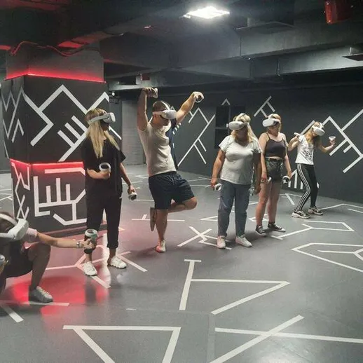 Группа людей в виртуальной реальности в игровом центре, развлекаются в вечернее время