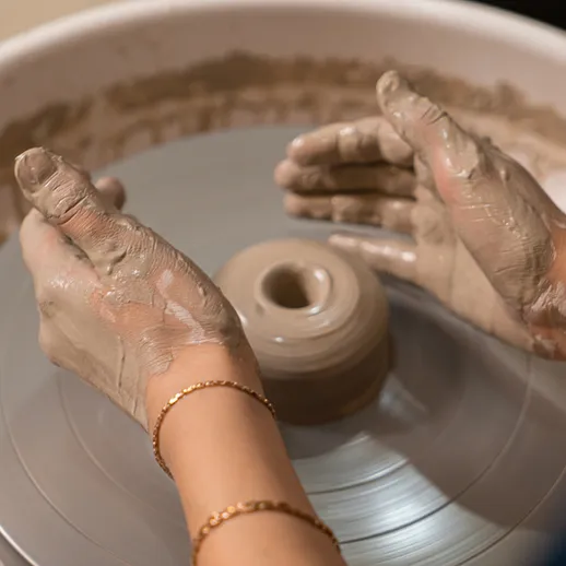 Изготовление керамической посуды на круге гончара в мастерской, руки в глине, вечернее занятие
