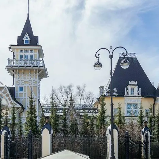 Исторический особняк в живописном парке на фоне голубого неба и густых деревьев