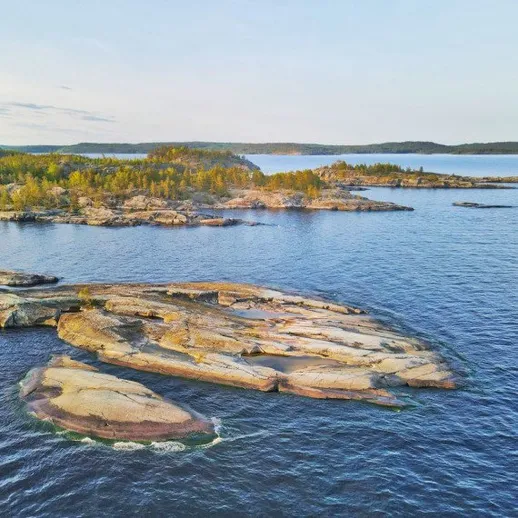 Спокойное утро на скалистом побережье у озера с зелеными деревьями вдали