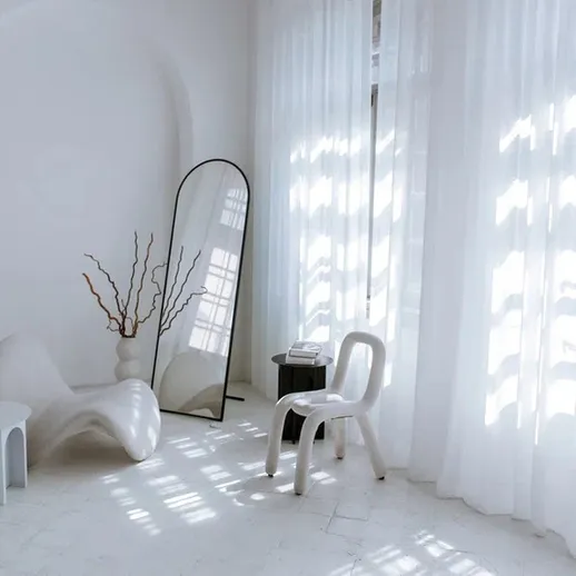 Просторное светлое помещение с белыми занавесками и минималистичной мебелью