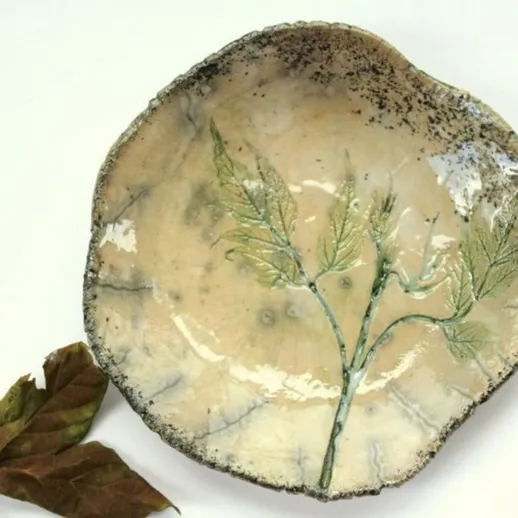 Керамическая тарелка с изображением листьев на белом фоне, выполненная вручную в ремесленной мастерской
