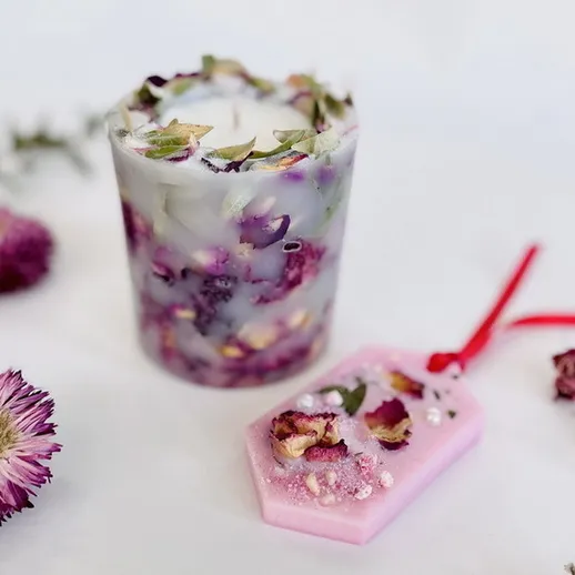 Свеча с цветами и ароматами, созданная в домашних условиях, рядом с декоративными элементами