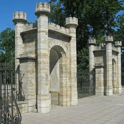 Архитектурные ворота в историческом парке с каменной кладкой и зелеными насаждениями рядом с ними