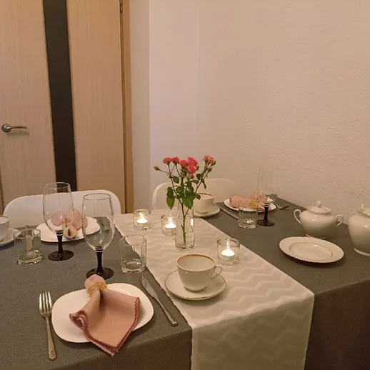 Уютный обеденный стол с посудой, цветами и свечами в спокойной обстановке вечера