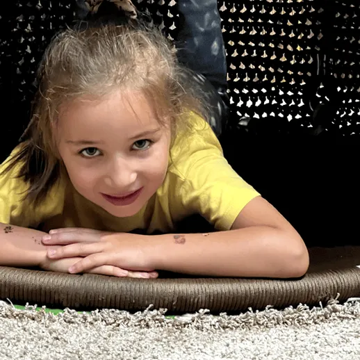 Девочка с короткими светлыми волосами играет в уютном игрушечном домике на улице