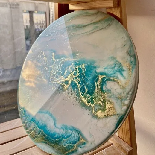 Эксклюзивная круглая доска из смолы с мраморным узором, лежащая на полке у окна в солнечное время