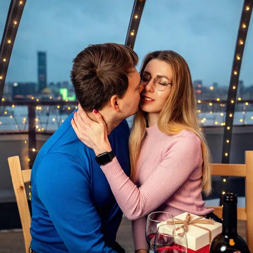 Романтический вечер пары в ресторане с огнями и городским пейзажем на фоне