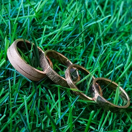 Кольца из золота на зеленом травяном фоне, размещенные в искусственной траве на солнечном свете