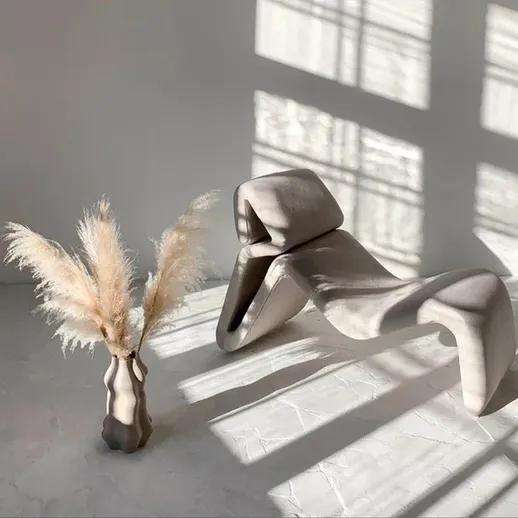 Скульптура и ваза с сухими цветами на фоне солнечного света в современном интерьере