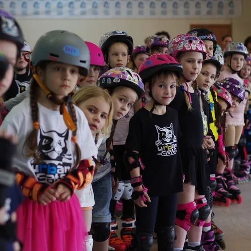 Дети в защитной экипировке занимаются роликовыми коньками в спортивном зале