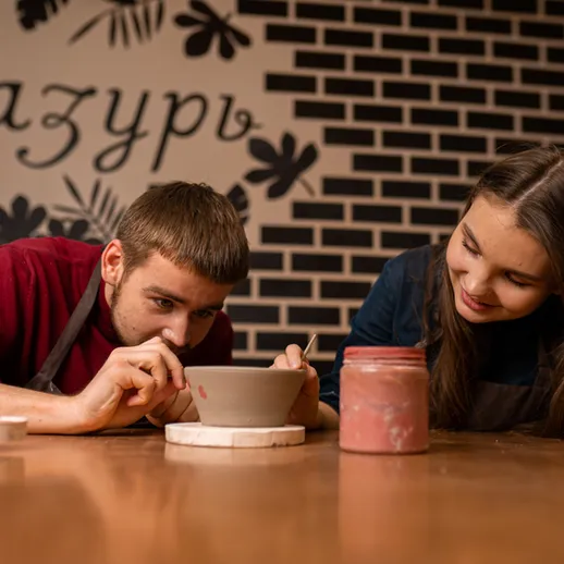 Молодые люди лепят горшок из глины в мастерской на занятиях по керамике