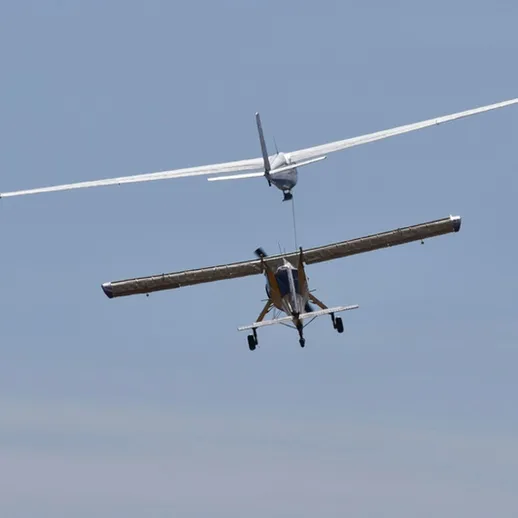 В воздухе выполняются манёвры между двух самолётов над открытой местностью в ясный день