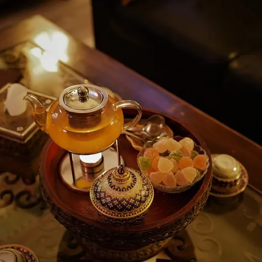 Традиционный чай в восточной чайной церемонии с десертами и кружащими огнями вечера
