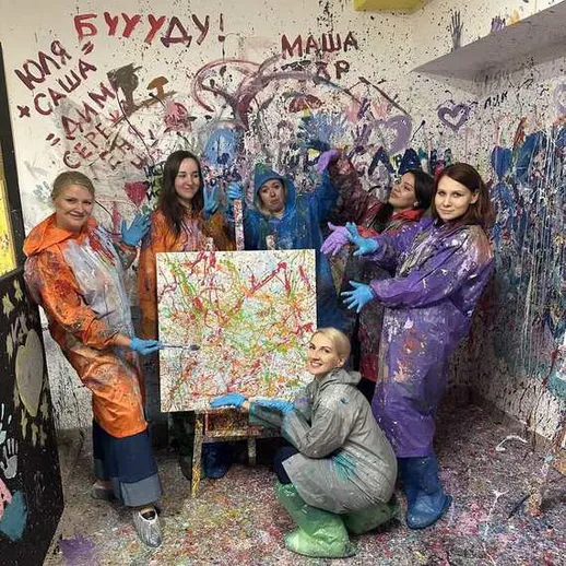 Группа женщин занимается абстрактной живописью в студии с яркими цветами и художественными надписями на стенах