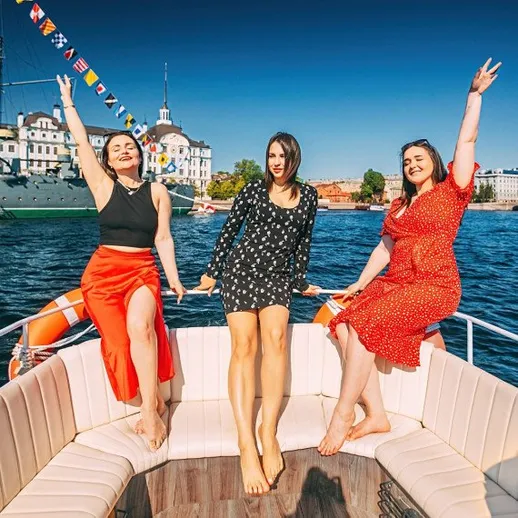 Три девушки на лодке наслаждаются солнечным днем на реке в центре города