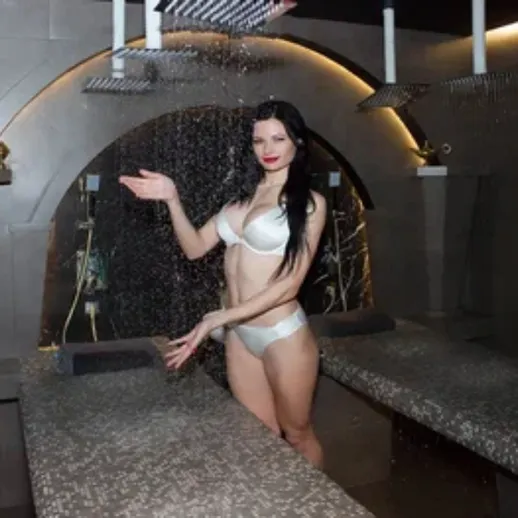 Открытое пространство спа-салона с девушкой в купальнике под водопадом в вечернее время