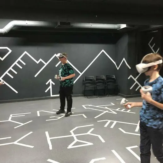 Трое подростков в виртуальной реальности играют в интерактивную игру в закрытом помещении