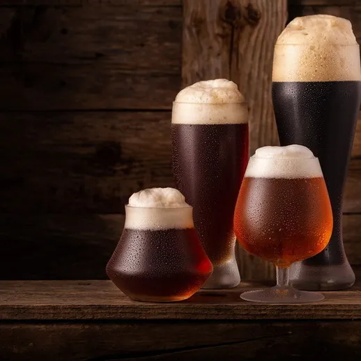 Разнообразие пивных бокалов на деревянном столе в уютном пабе вечером