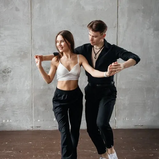 Парень и девушка танцуют в студии танца, украшенной серыми стенами, в вечернее время