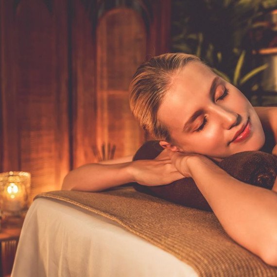 Женщина отдыхает на массажном столе в спа-салоне в вечернее время Женщина отдыхает на массажном столе в спа-салоне в вечернее время