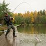 Рыбак ловит рыбу осенью на озере в лесу - превью 1