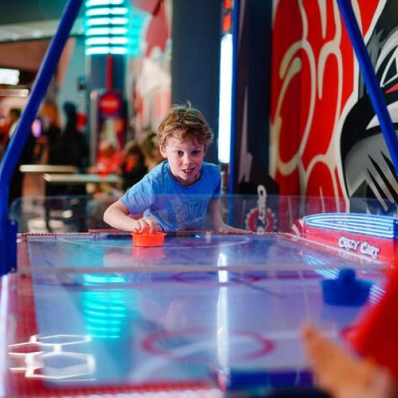 Мальчик играет в хоккейный автомат с другим ребенком в развлекательном центре. Главное фото