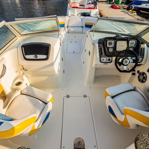 Катер на причале с белыми и желтыми сиденьями в солнечный день