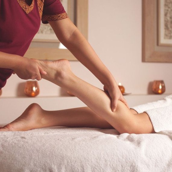 Массажист выполняет массаж ног в спа-салоне во время процедуры для клиента Массажист выполняет массаж ног в спа-салоне во время процедуры для клиента