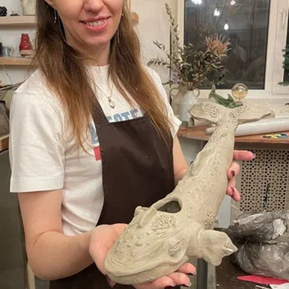 Женщина демонстрирует керамическую скульптуру рыбы в творческой мастерской. Фото 9