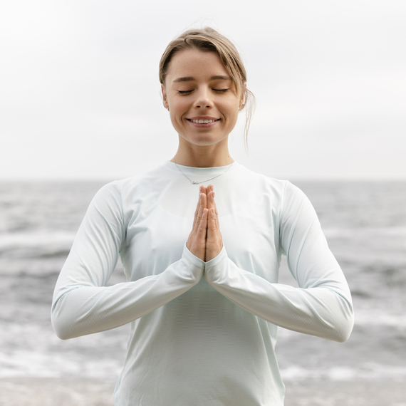 Йога на свежем воздухе: женщина медитирует на горной вершине с облаками в окружении. Главное фото