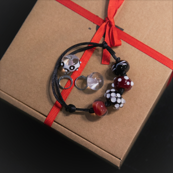 Украшение на черной ленте рядом с коробкой с красной лентой Украшение на черной ленте рядом с коробкой с красной лентой