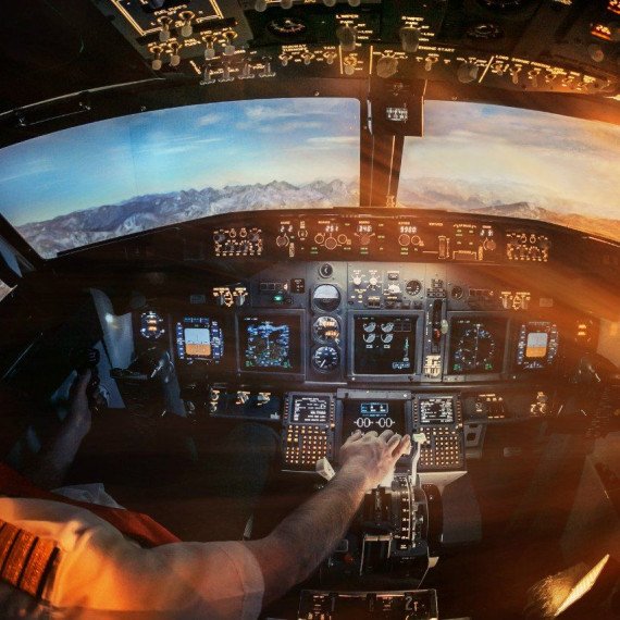 Пилот управляет самолетом в кабине во время полета над горами при заходе солнца