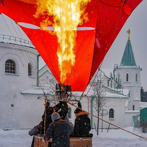 Несколько людей готовят воздушный шар к полету на снежном зимнем фестивале в старинном российском городе. Фото 22