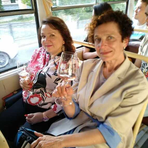 Две женщины наслаждаются закатом и бокалом вина в автобусе во время вечерней прогулки по городу. Фото 6