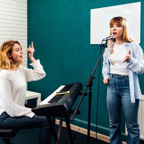 Женщина поет на сцене, а другая учит ее vocal техники в студии. Фото 4