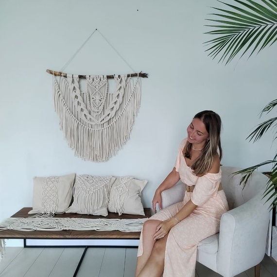 Женщина в розовом платье сидит на диване в светлом интерьере с украшениями Женщина в розовом платье сидит на диване в светлом интерьере с украшениями