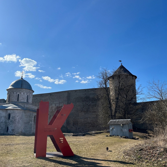 Красная буква K на фоне старинной крепости и голубого неба в историческом центре города. Фото 5