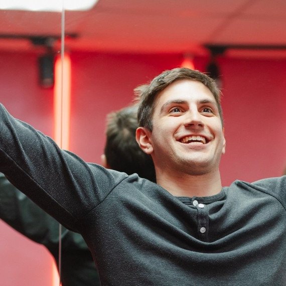 Парень с радостным выражением лица в помещении с ярким освещением