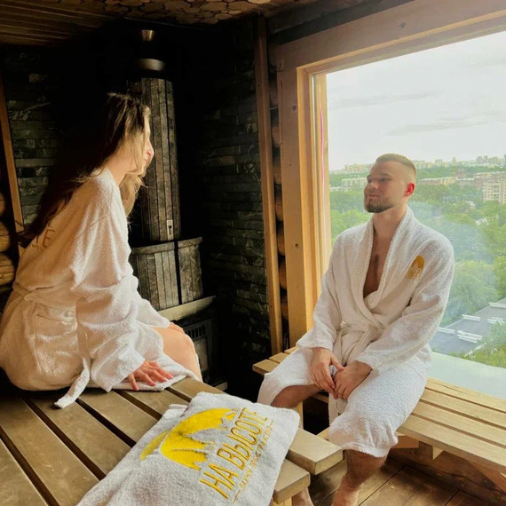 В сауне два человека разговаривают и отдыхают у окна с видом на город