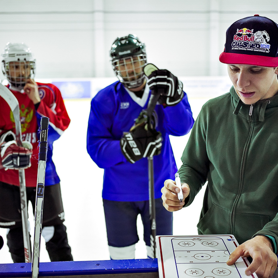 Тренировка хоккеистов на льду с наставником, обсуждающим игровую стратегию в ледовом дворце