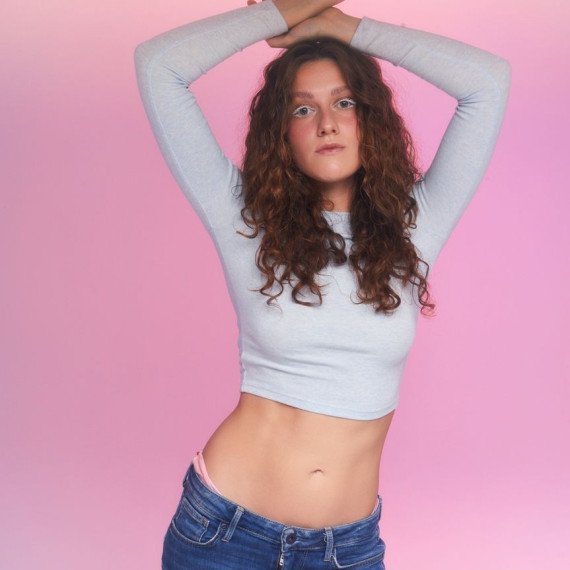 девушка позирует на фоне розового света с поднятыми руками девушка позирует на фоне розового света с поднятыми руками