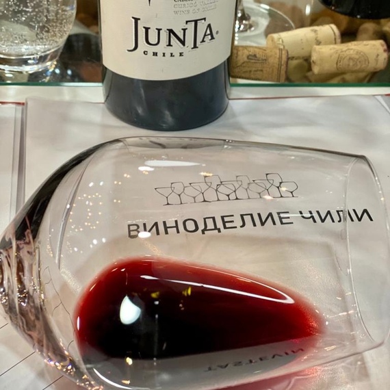 Вино из Чили в стакане с наклоном на столе, отражая вечернюю атмосферу дегустации