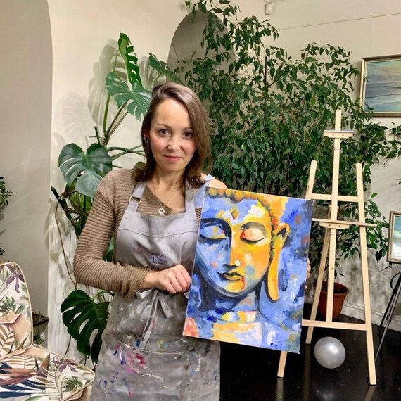 Женщина показывает свою картину с изображением Будды в студии искусства