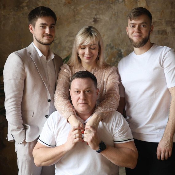 Семейная встреча в студии, четверо людей позируют в помещении с кирпичной стеной